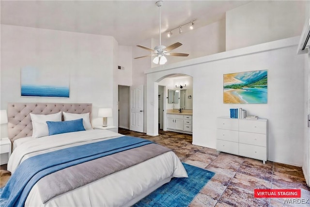 bedroom featuring arched walkways, visible vents, ensuite bathroom, stone finish flooring, and high vaulted ceiling