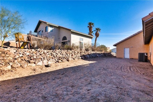 view of side of home featuring central AC and stucco siding