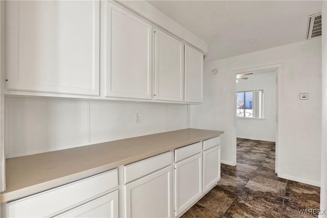 kitchen featuring light countertops, white cabinetry, visible vents, and baseboards