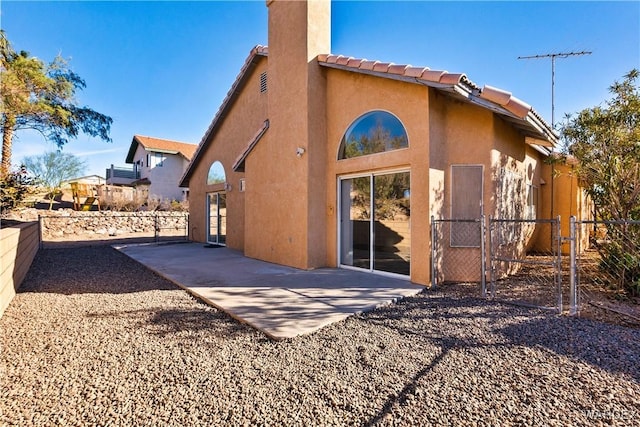 back of house featuring a tiled roof, fence, a patio, and stucco siding