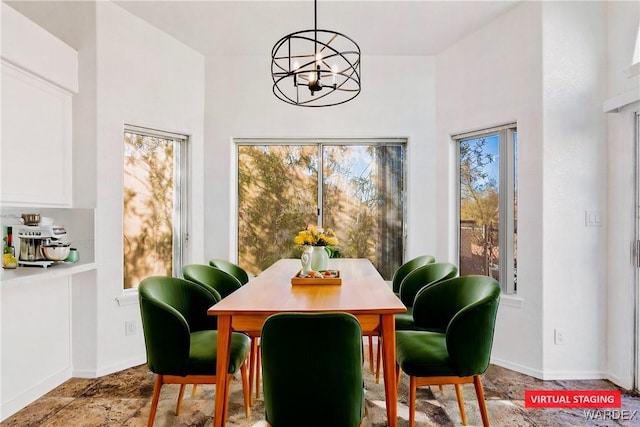 dining room featuring a chandelier, plenty of natural light, and baseboards