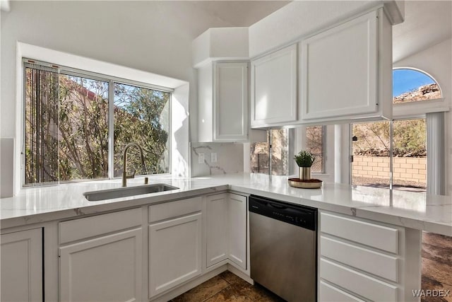 kitchen featuring tasteful backsplash, dishwasher, light stone counters, white cabinetry, and a sink