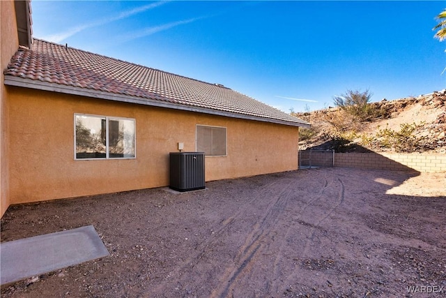 view of side of property with a tile roof, fence, cooling unit, and stucco siding