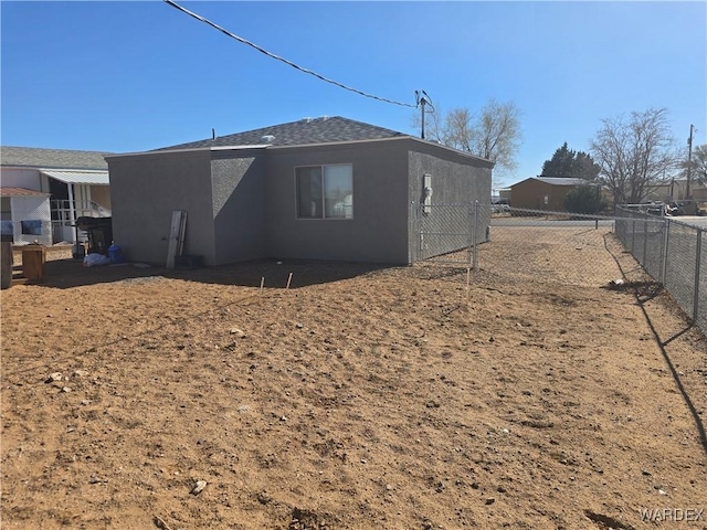 rear view of house featuring stucco siding and fence