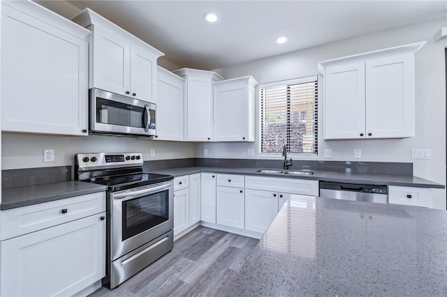 6102 S Scorpion Ln, Fort Mohave, AZ 86426 - kitchen with stainless steel appliances, white cabinetry, recessed lighting, dark stone countertops, and light wood-style floors