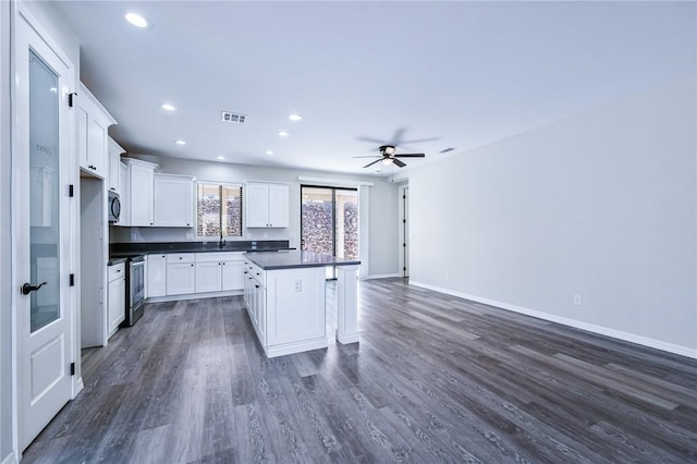 6102 S Scorpion Ln, Fort Mohave, AZ 86426 - kitchen with black microwave, dark countertops, stainless steel electric range, dark wood finished floors, and white cabinetry