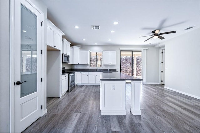6102 S Scorpion Ln, Fort Mohave, AZ 86426 - kitchen featuring stainless steel appliances, a center island, dark countertops, a ceiling fan, and white cabinetry