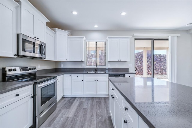 6102 S Scorpion Ln, Fort Mohave, AZ 86426 - kitchen with stainless steel appliances, white cabinets, light wood finished floors, recessed lighting, and dark stone counters