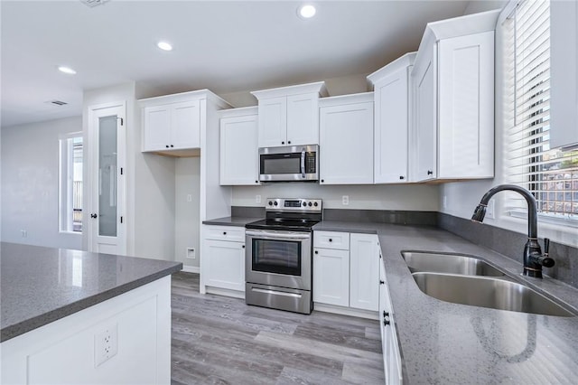 6102 S Scorpion Ln, Fort Mohave, AZ 86426 - kitchen featuring appliances with stainless steel finishes, white cabinetry, recessed lighting, light wood-style flooring, and dark stone counters