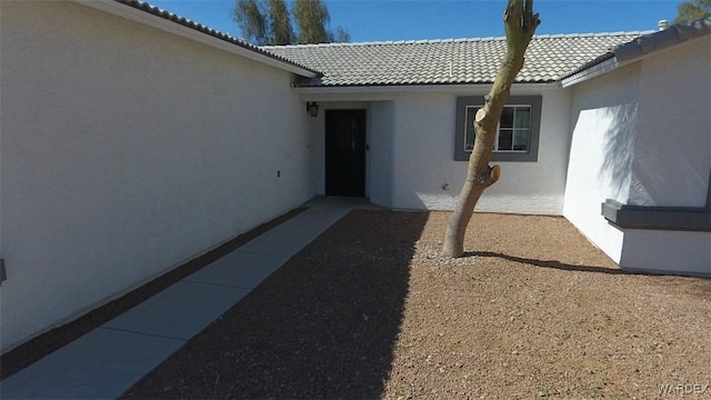 entrance to property with a tiled roof and stucco siding