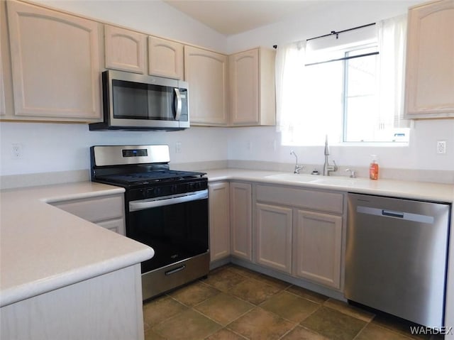 kitchen with appliances with stainless steel finishes, light countertops, and a sink