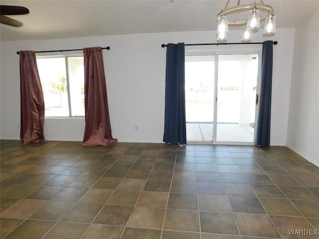 unfurnished room featuring ceiling fan with notable chandelier and dark tile patterned floors