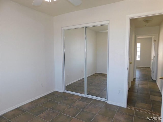 unfurnished bedroom with a ceiling fan, a closet, and baseboards