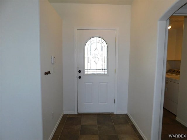 entryway with washer / dryer, dark tile patterned floors, and baseboards