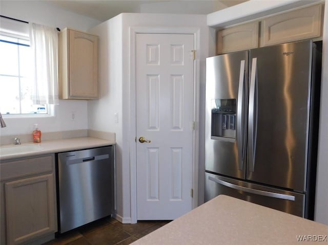 kitchen featuring dark tile patterned floors, stainless steel appliances, a sink, and light countertops