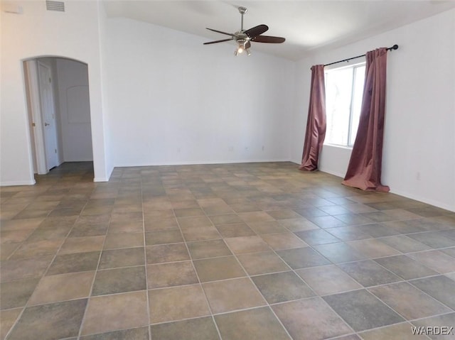 tiled empty room with arched walkways, visible vents, vaulted ceiling, and ceiling fan