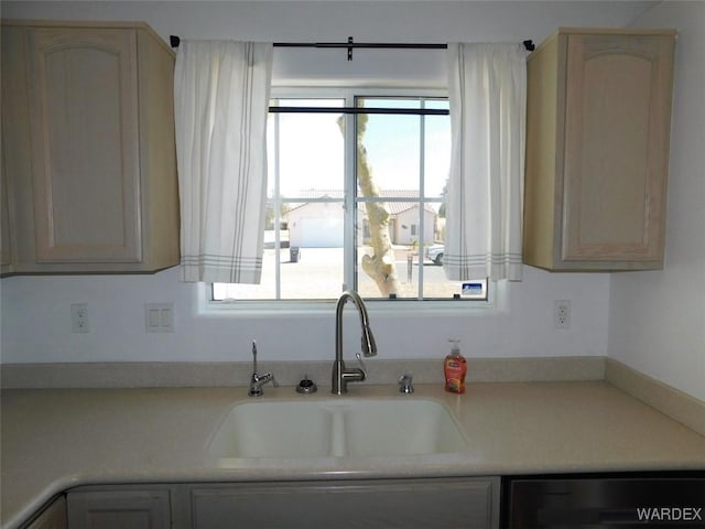 kitchen featuring light countertops, a sink, and dishwashing machine