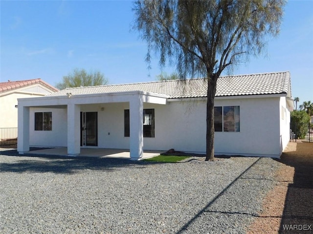 back of house with a tiled roof, a patio, and stucco siding