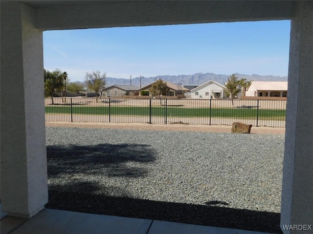 view of yard featuring fence, a mountain view, and a residential view