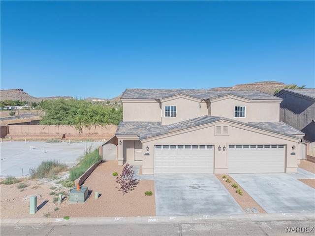 view of front of property with a mountain view, concrete driveway, and stucco siding