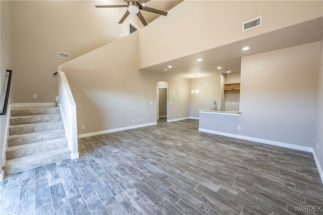 unfurnished living room featuring visible vents, dark wood finished floors, and stairway