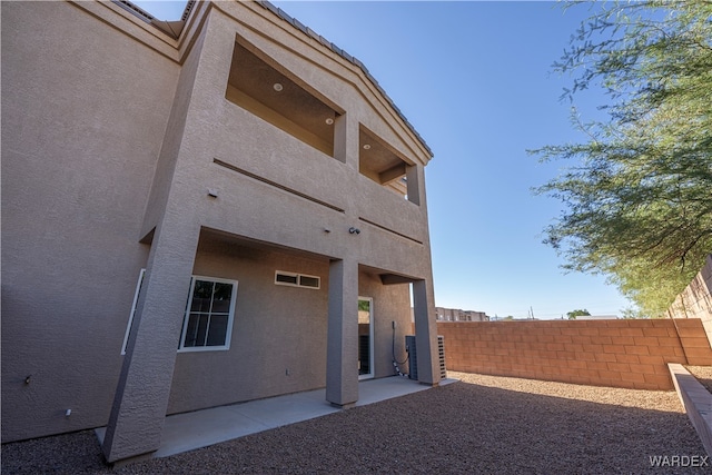 rear view of house with a patio area, fence, and stucco siding