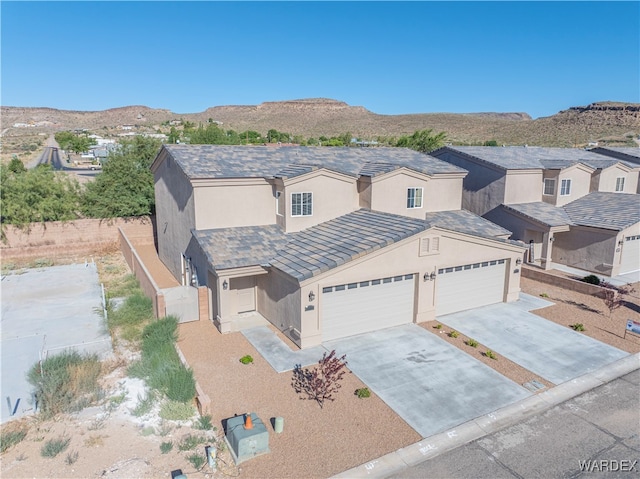 view of front of property featuring a mountain view, a garage, driveway, a residential view, and stucco siding