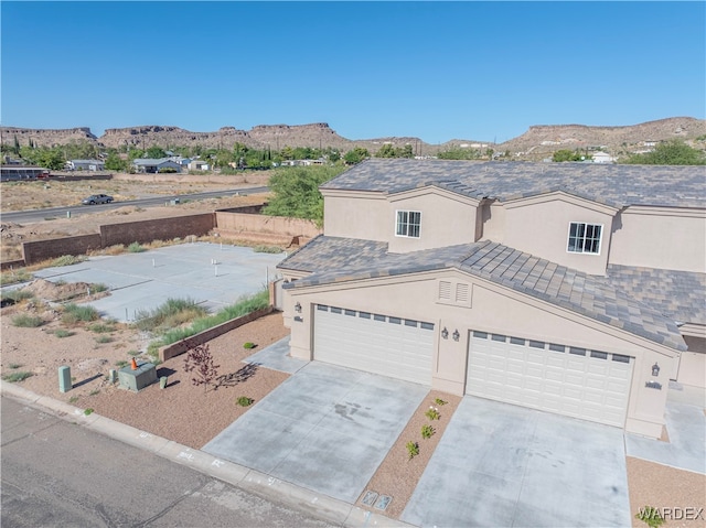 view of front of property featuring a garage, concrete driveway, a mountain view, and stucco siding