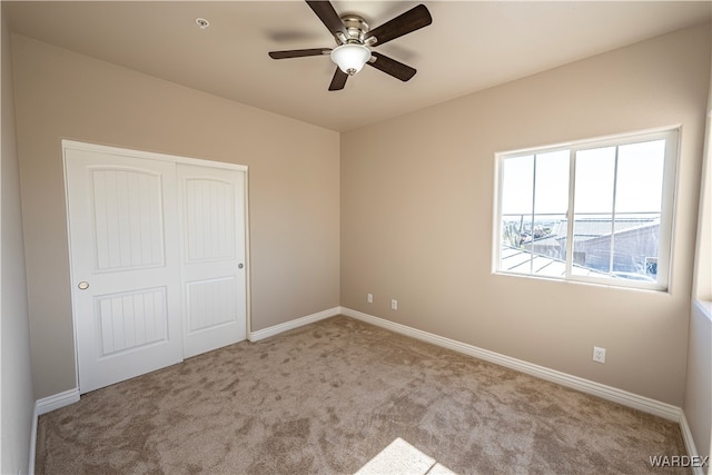 unfurnished bedroom with ceiling fan, baseboards, a closet, and light colored carpet