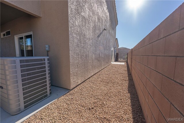 view of property exterior with central AC, fence, and stucco siding