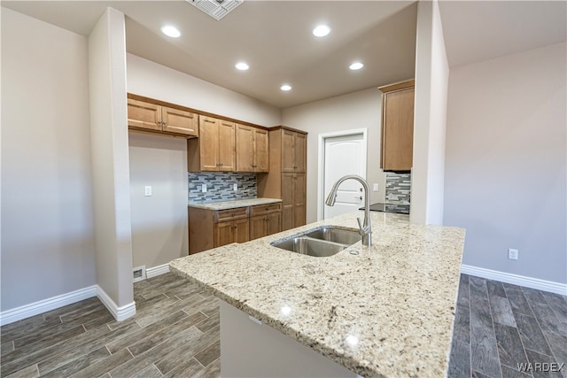 kitchen featuring light stone counters, visible vents, a sink, and a peninsula