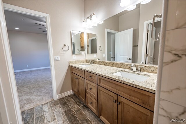 bathroom featuring double vanity, wood finish floors, a sink, and baseboards