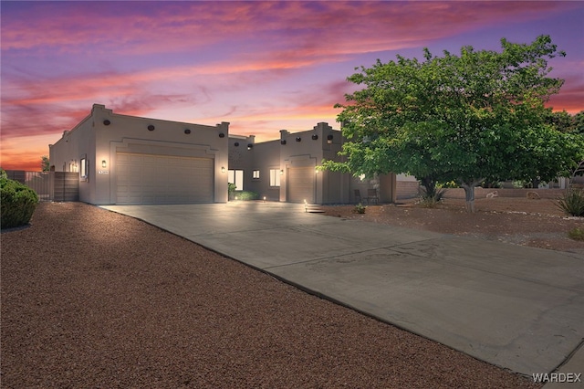 pueblo-style home with driveway, an attached garage, and stucco siding