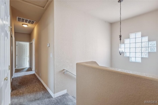 corridor featuring baseboards, visible vents, and dark carpet