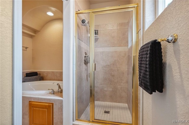 bathroom featuring a garden tub, a shower stall, and a textured wall