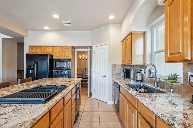 kitchen with black appliances, light stone counters, a sink, and tasteful backsplash