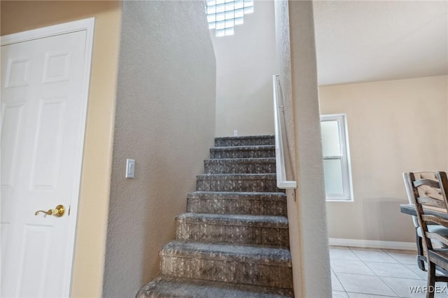 staircase featuring baseboards and tile patterned floors