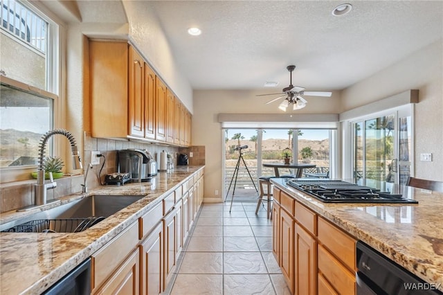 kitchen featuring light stone counters, backsplash, a sink, a textured ceiling, and black appliances