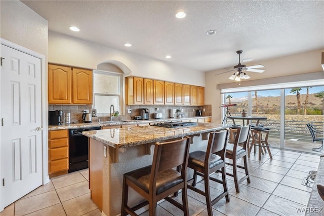 kitchen featuring tasteful backsplash, a center island, dishwasher, and light stone countertops