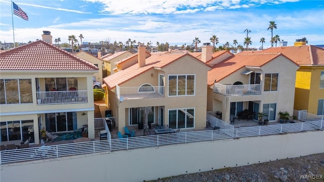 rear view of house featuring a tile roof, a fenced backyard, a residential view, and stucco siding