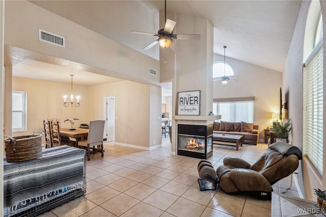 living area featuring light tile patterned flooring, a multi sided fireplace, and visible vents