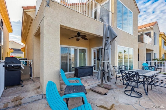 view of patio / terrace featuring a ceiling fan, area for grilling, a balcony, fence, and outdoor dining space