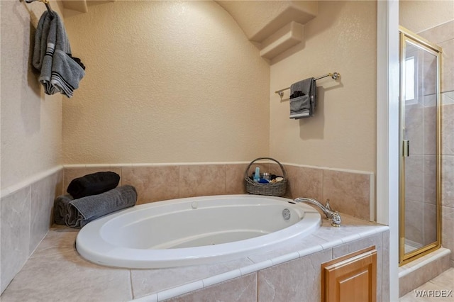 full bathroom with a garden tub, a textured wall, and a stall shower