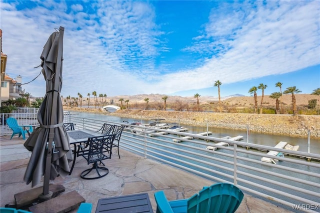 view of patio with a balcony and a water and mountain view