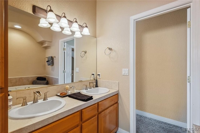 full bathroom with a textured wall, double vanity, and a sink