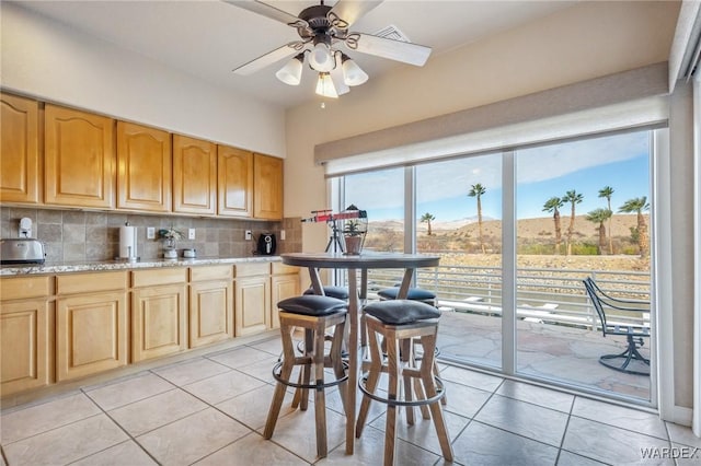 kitchen featuring visible vents, decorative backsplash, ceiling fan, a mountain view, and light tile patterned flooring