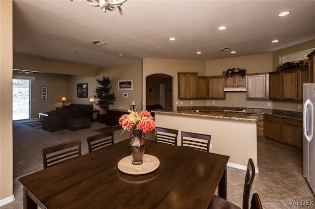 tiled dining area featuring visible vents, arched walkways, and recessed lighting