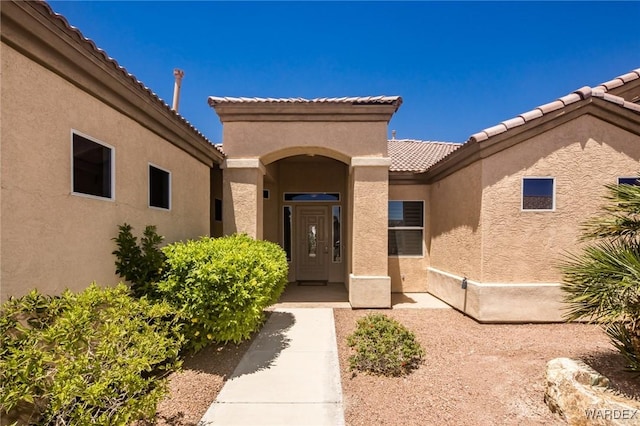 property entrance with a tiled roof and stucco siding