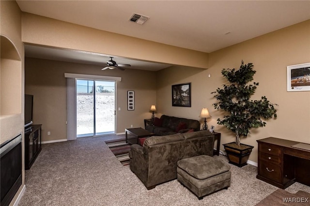 living room with light carpet, a glass covered fireplace, visible vents, and baseboards