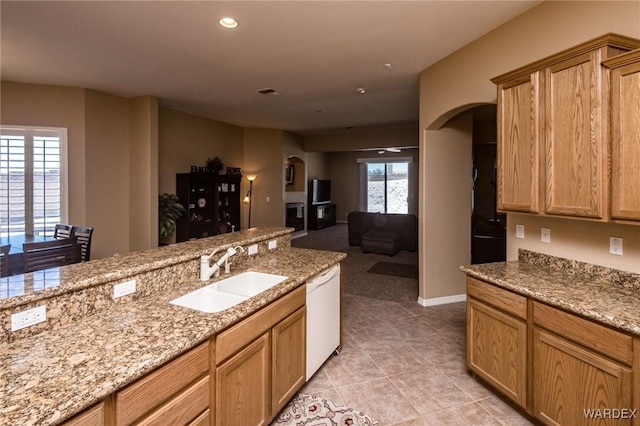 kitchen featuring arched walkways, open floor plan, a sink, and dishwasher